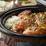 easy crockpot meals Honey garlic chicken pieces in a slow cooker, coated in a glossy sauce, topped with green onions, served alongside white rice.