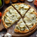 A delicious pickle pie pizza topped with sliced pickles and melted cheese.